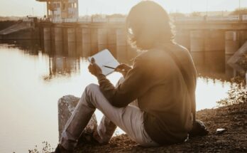 success minded lady journaling sitting by the a river