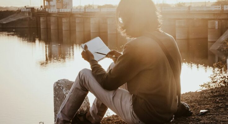 success minded lady journaling sitting by the a river